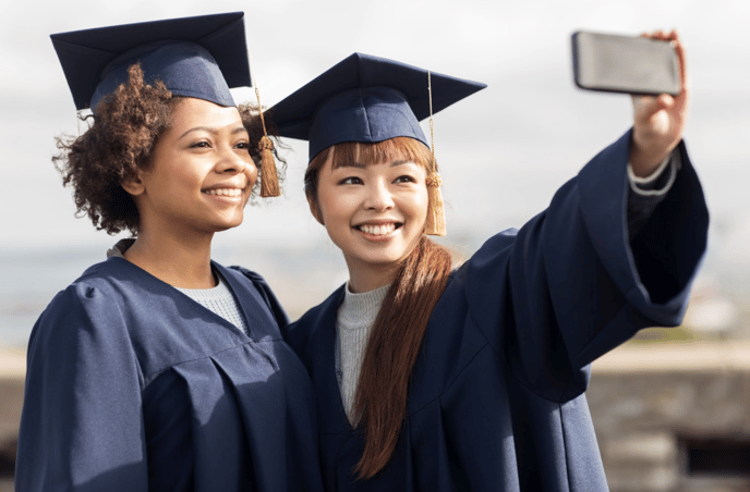 Two students in graduation gowns taking a selfie