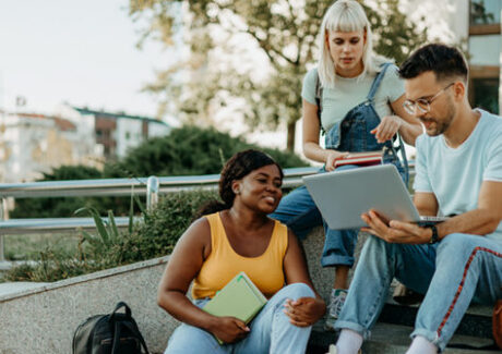 a group of students discussing something by the campus stairwell