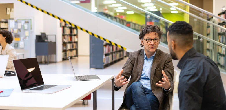 student advisor discussing something in the library with the student